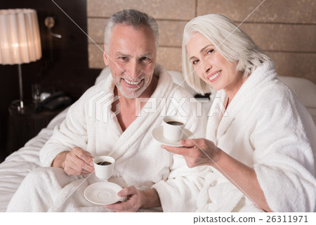 Happy pleasant aged couple drinking coffee on the Happy pleasant aged couple drinking coffee on the 26311971
