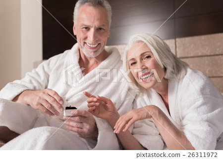 Smiling aged man giving a present to an old woman Smiling aged man giving a present to an old woman 26311972