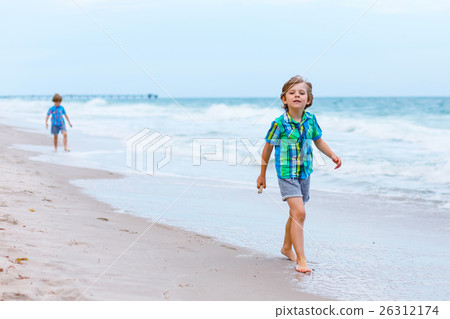 Two little kids boys running on the beach of ocean Two little kids boys running on the beach of ocean 26312174