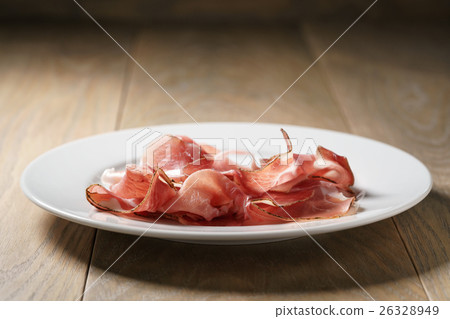 speck slices on white plate on old wood table 26328949
