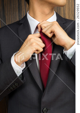 Asian man in a suit correcting his red necktie 26329932