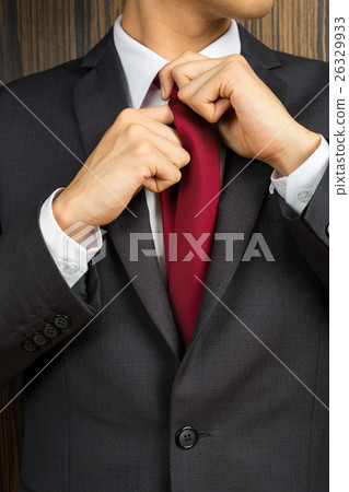 Asian man in a suit correcting his red necktie Asian man in a suit correcting his red necktie 26329933