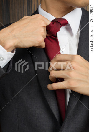 Asian man in a suit correcting his red necktie 26329934