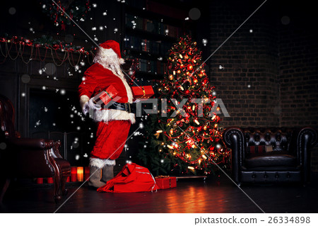 Christmas night, Santa Claus puts gifts under the  26334898