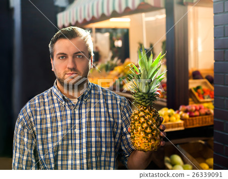 Man holds ripe pineapple in hands. Man holds ripe pineapple in hands. 26339091