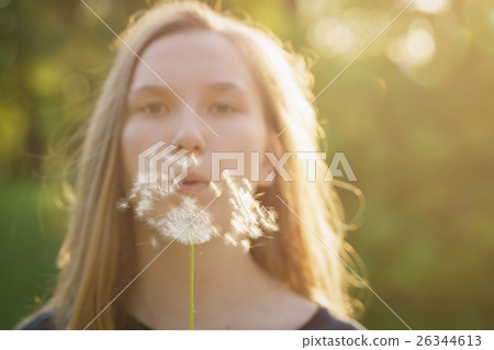 teen girl blowing dandelion to the camera teen girl blowing dandelion to the camera 26344613