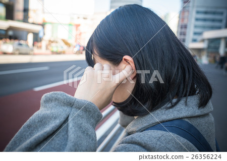 A woman holding an ear hole 26356224