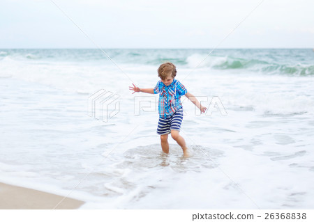 little kid boy running on the beach of ocean 26368838