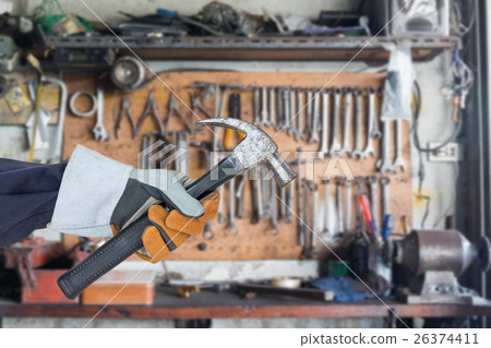 Hand in glove holding hammer with tools hanging 26374411