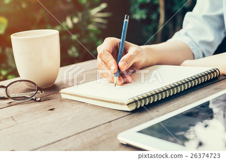 Female hand with pencil writing on notebook. 26374723
