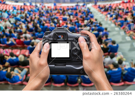 Hand holding the camera over Top view of Abstract blurred photo crowd of spectators on a stadium with a football match, sport background concept 26380264