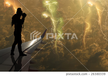 silhouette of man who taking photo of the thunder lightnings over the clouds and storm on airplane wing, Challenge business concept silhouette of man who taking photo of the thunder lightnings over the clouds and storm on airplane wing, Challenge business concept 26380339