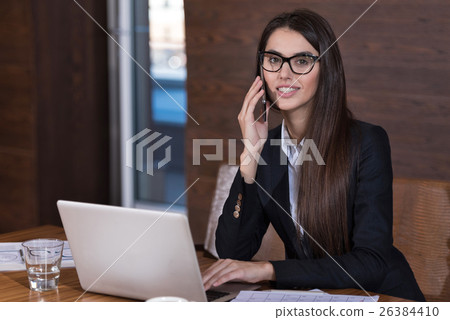 Smiling woman using a cellphone in an office Smiling woman using a cellphone in an office 26384410
