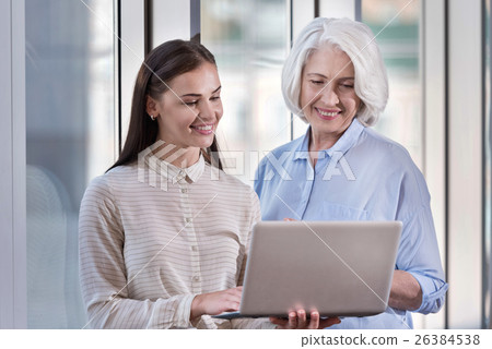 Young woman and her elderly boss working on laptop Young woman and her elderly boss working on laptop 26384538