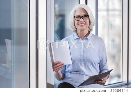 Elderly woman posing with documents in an office Elderly woman posing with documents in an office 26384544