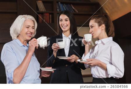 Amused colleagues drinking coffee in an office Amused colleagues drinking coffee in an office 26384566