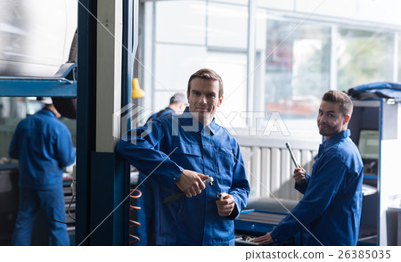 Cheerful auto mechanics holding tools Cheerful auto mechanics holding tools 26385035
