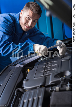 Cheerful handsome mechanic working in auto center Cheerful handsome mechanic working in auto center 26385287