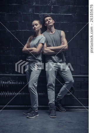 Concentrated dancers standing near the black wall 26385676