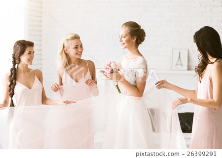 Smiling bridesmaids holding the dress of the bride 26399291