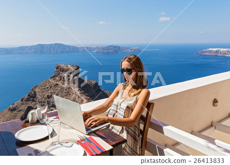 Woman working at a computer on the seafront. 26413833