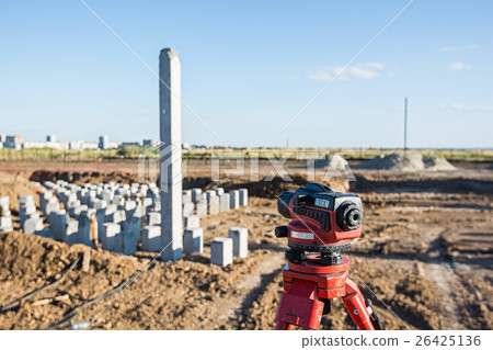 Theodolite in front of piles field 26425136