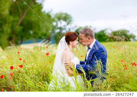 Happy wedding couple in pink poppy field 26427247