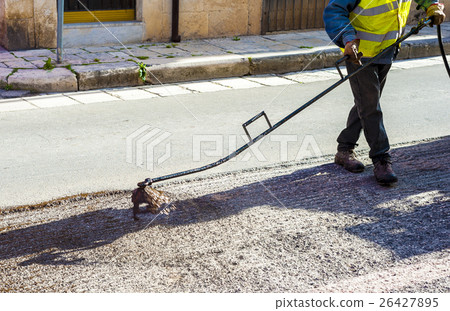 Road worker spraying bitumen emulsion  26427895