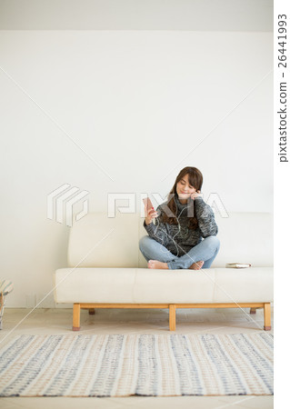 A young lady listening to music while relaxing on the sofa in the living room A young lady listening to music while relaxing on the sofa in the living room 26441993