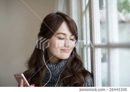 站立在窗口的一個少婦,當聽到在智能手機時的音樂 站立在窗口的一個少婦,當聽到在智能手機時的音樂 26443300