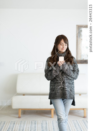A young woman who enjoys music with a smartphone A young woman who enjoys music with a smartphone 26443315
