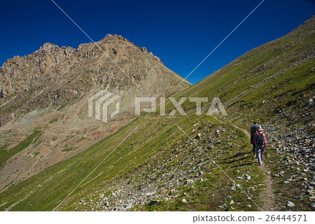 Group of people hiking over green grassy mountain Group of people hiking over green grassy mountain 26444571
