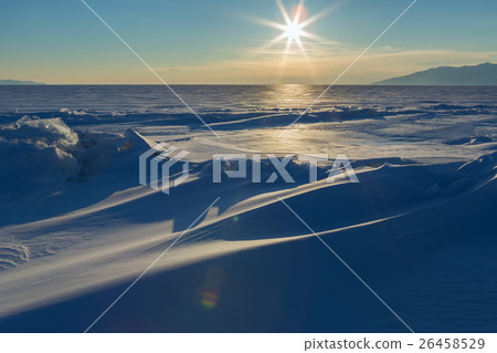 Sun sets over the snow-covered ice hummocks of 26458529