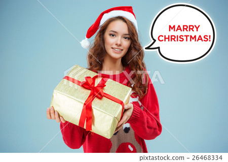 Girl dressed in santa hat with a Christmas gift Girl dressed in santa hat with a Christmas gift 26468334