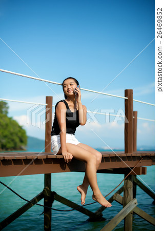 Asian girl talking on the phone at a pier 26469852