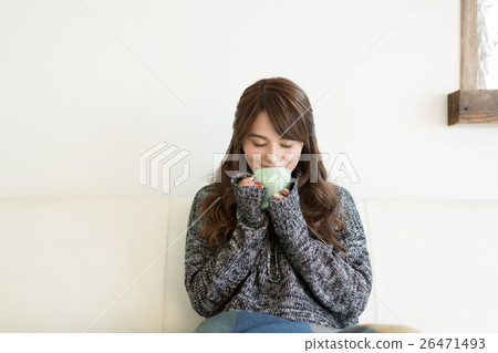 喝在沙發的一位小姐熱的咖啡在客廳 喝在沙發的一位小姐熱的咖啡在客廳 26471493