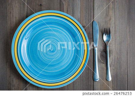empty blue round plate with fork and knife on dark 26476253