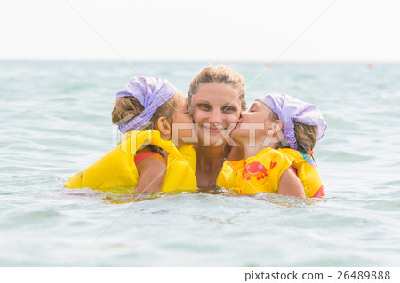 Daughters kiss mom swimming in the sea Daughters kiss mom swimming in the sea 26489888