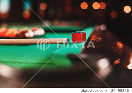 Cue and chalk on a pool table.  26499206
