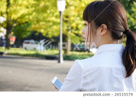 A young business woman operating a smartphone with a smile A young business woman operating a smartphone with a smile 26533579