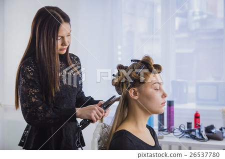 Long hair being straightened with iron by stylist 26537780
