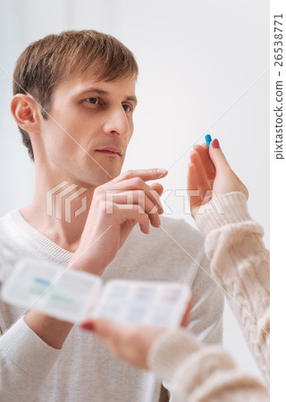 Unhappy young man taking a pill 26538771