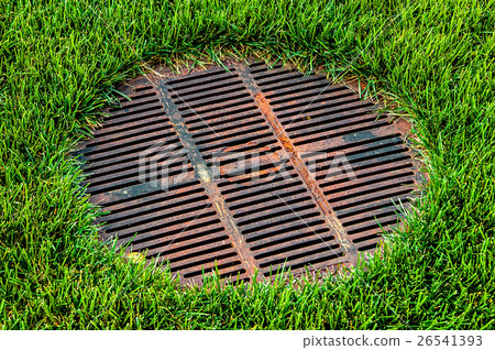 Gridded sewer manhole on green lawn Gridded sewer manhole on green lawn 26541393