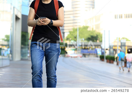 young woman walking with smart phone in city 26549278