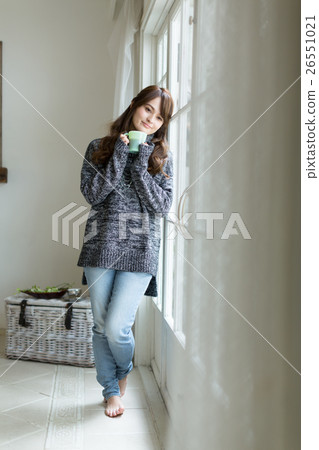 A young woman drinking hot coffee at the window side 26551021