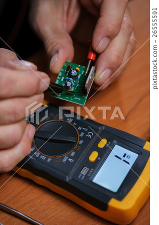 Electrician checking microcircuit with multimeter Electrician checking microcircuit with multimeter 26555591