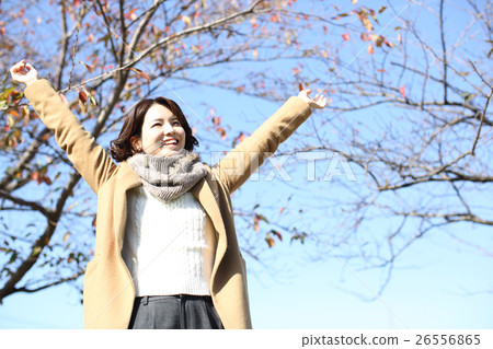 A woman stretching by wearing a coat 26556865