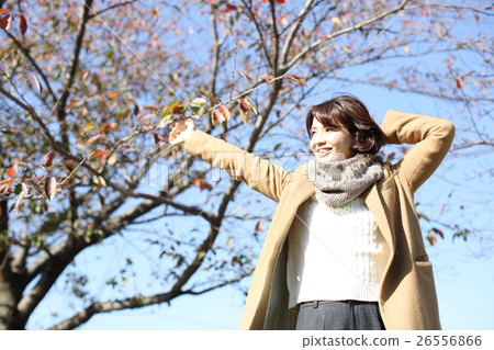 A woman stretching by wearing a coat 26556866