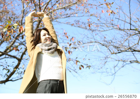 A woman stretching by wearing a coat A woman stretching by wearing a coat 26556870