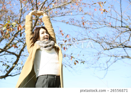 A woman stretching by wearing a coat A woman stretching by wearing a coat 26556871